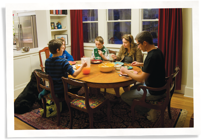 Family dinner next to window with Indow insert, an alternative to thermal pane window replacements.