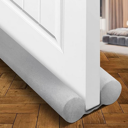 Holikme Twin Door Draft Stopper in gray, pictured stopping drafts coming through white door