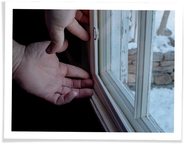Adjusting the corner of an Indow insert: winter scene visible through acrylic insert & glass window.