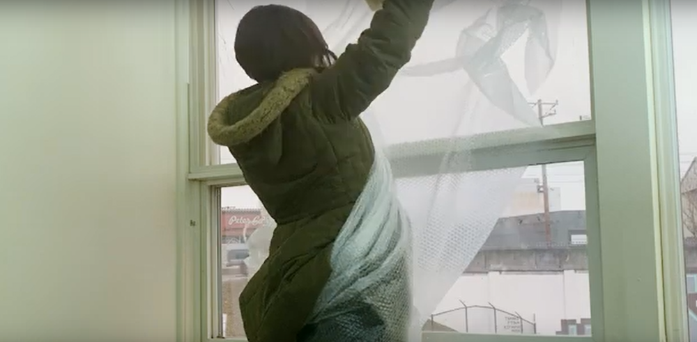 woman adding bubble wrap windows for insulation