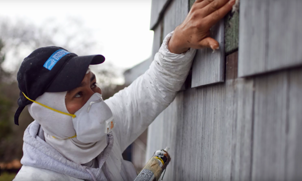 person with mask adding acoustic caulk to siding for soundproofing