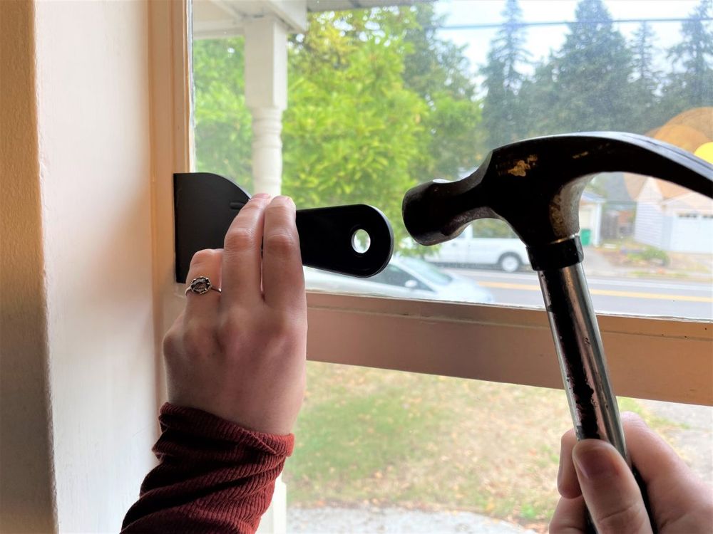 Hammering putty knife in a paint sealed crevice of a window painted shut