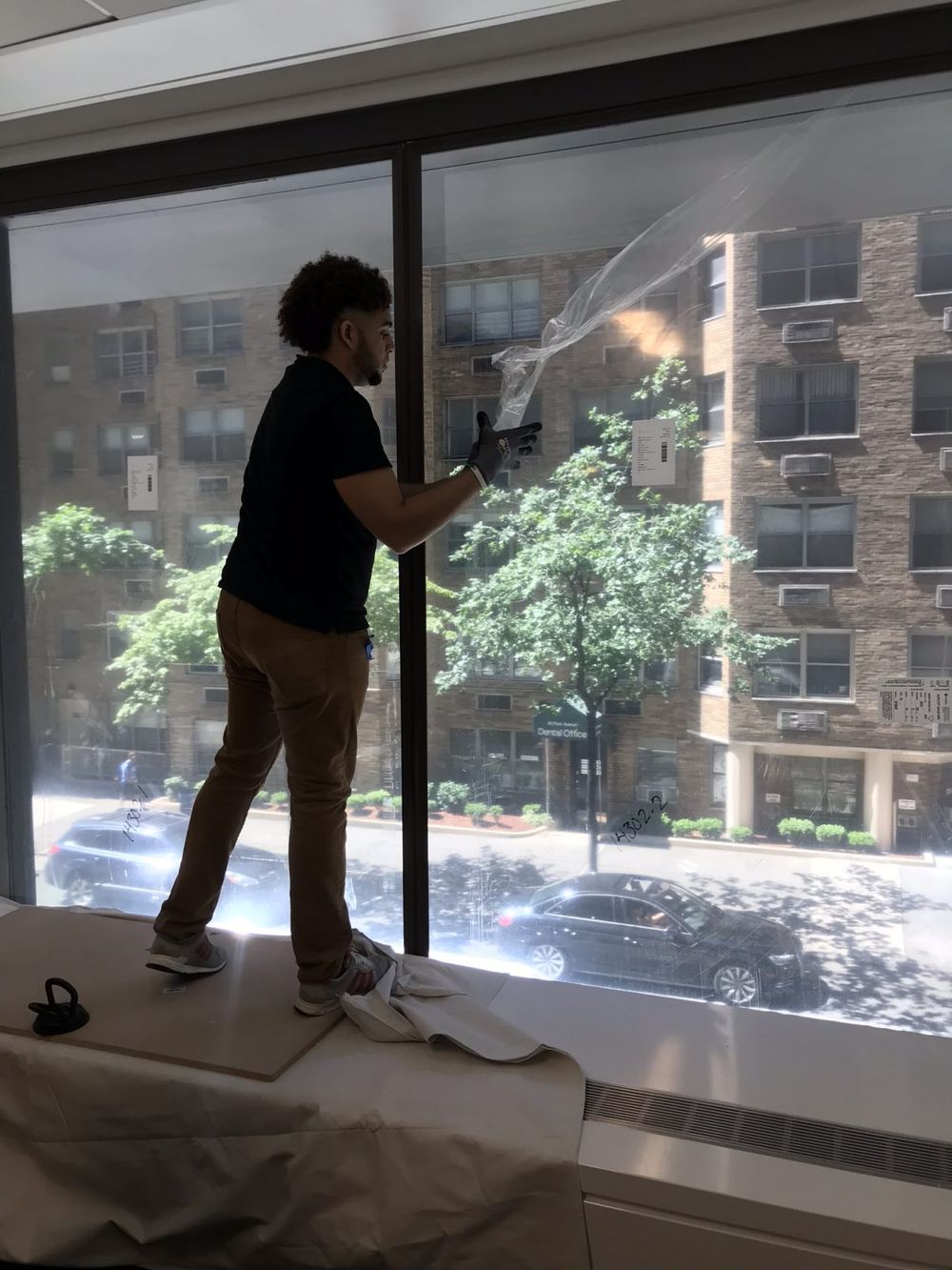 Man installing Indow window inserts in NYC. Retrofitting windows makes buildings more sustainable.