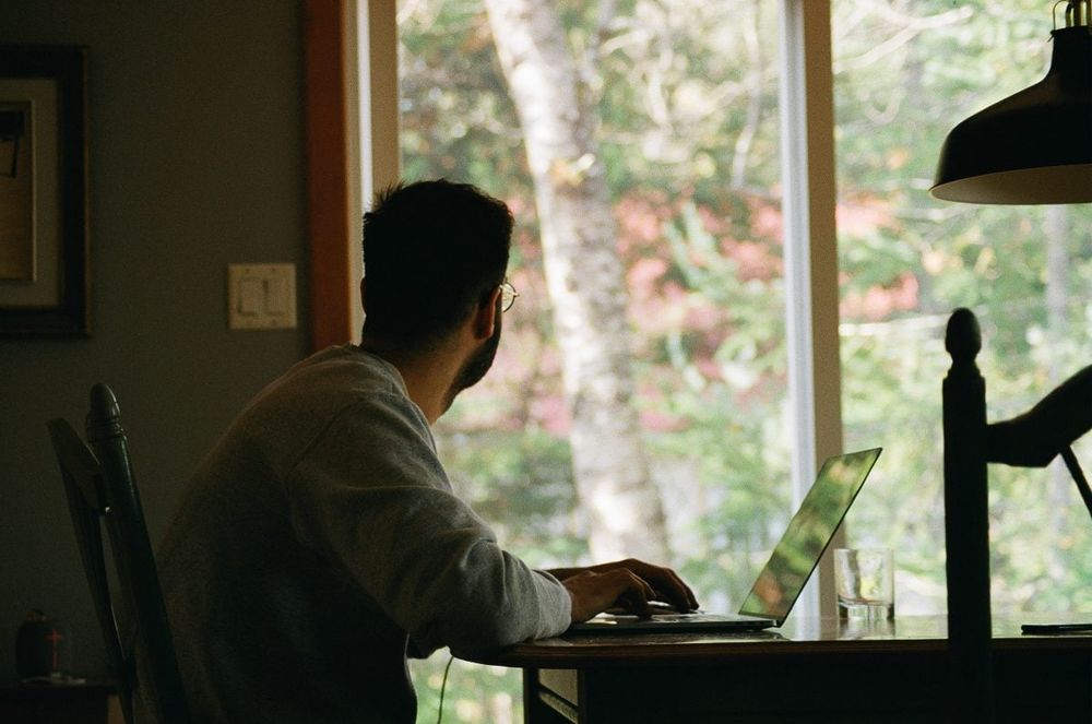 man sitting at a desk looking out the window