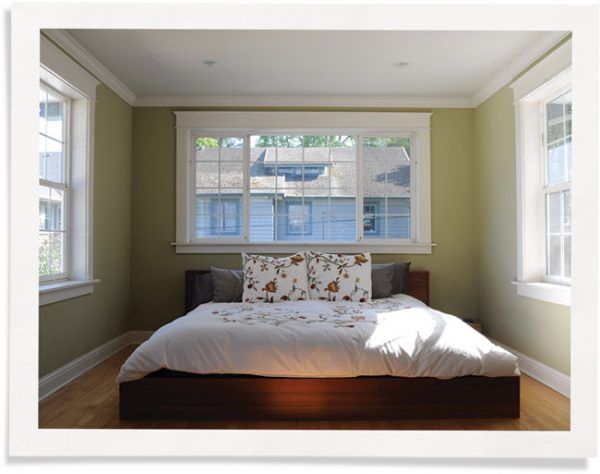 Well-lit bedroom with three large windows without curtains