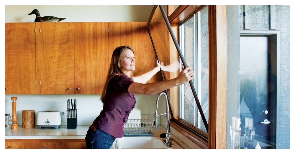 A woman installing window inserts to her kitchen window.