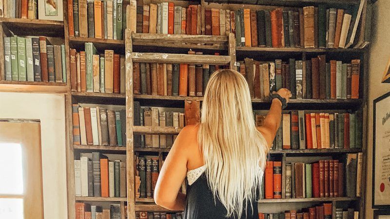 Woman reaching to a book in a home library