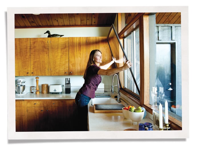 woman installing Indow window insert in kitchen window for bay area noise control