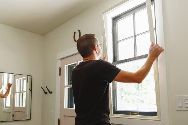 man installing window inserts for how to keep a mudroom warm