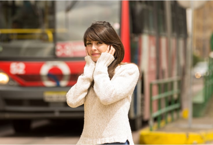 woman covering her ears from the loud noise affecting her health