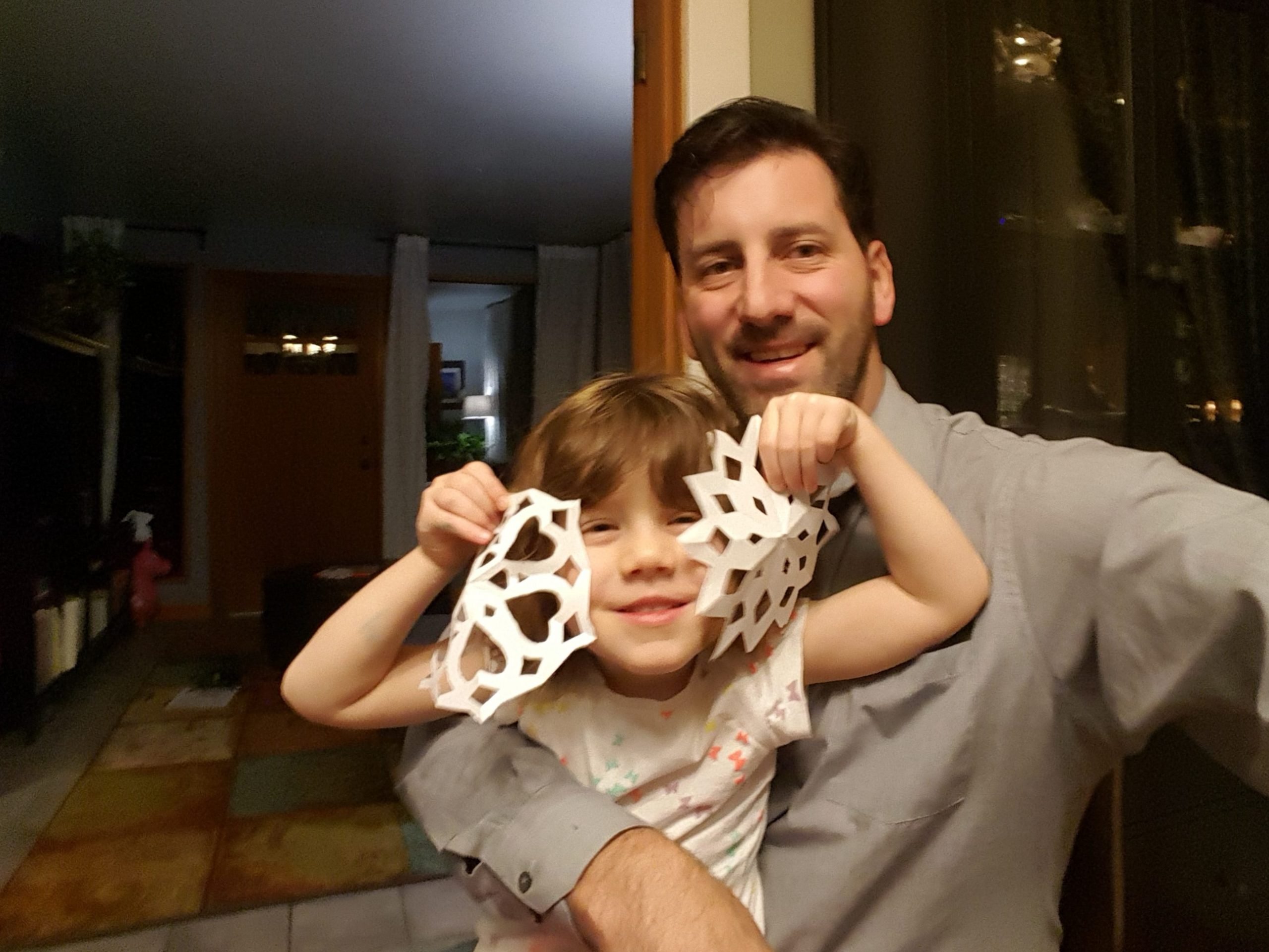 father and child creating holiday christmas window decorations - paper cut snowflakes