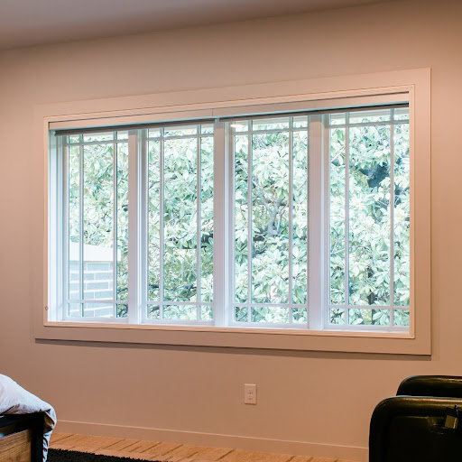 The interior of a home with a view of the sunny outdoors. Indow window inserts are installed on these bedroom windows. 