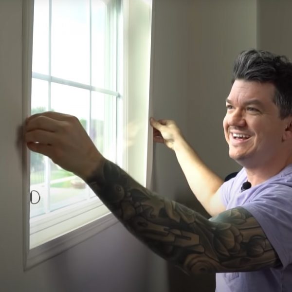 A person wearing a purple shirt is installing a window insert.